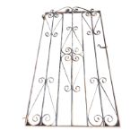 A wrought iron garden gate with scrolled decoration to vertical spindles in rectangular frame,