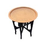 A circular brass coffee table, the tray top with Egyptian style panels framed by waved rim, the