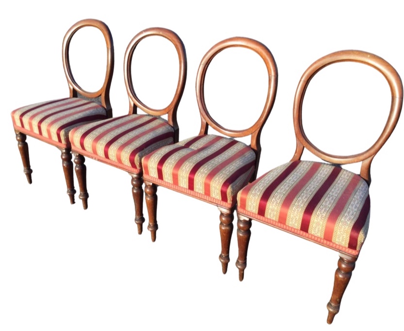 A set of four Victorian mahogany balloon-back dining chairs with stuffover upholstered seats