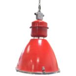 A large red painted industrial style hanging light supported by chain, with circular drum type
