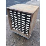 An industrial cabinet, the metal chest with fifty small drawers mounted with label holder handles,
