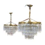 A pair of hanging brass chandeliers, each with three circular tiers of crystal drops supported by