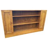 A rectangular mahogany open bookcase cabinet, with three open shelves flanked by panelled cupboards,