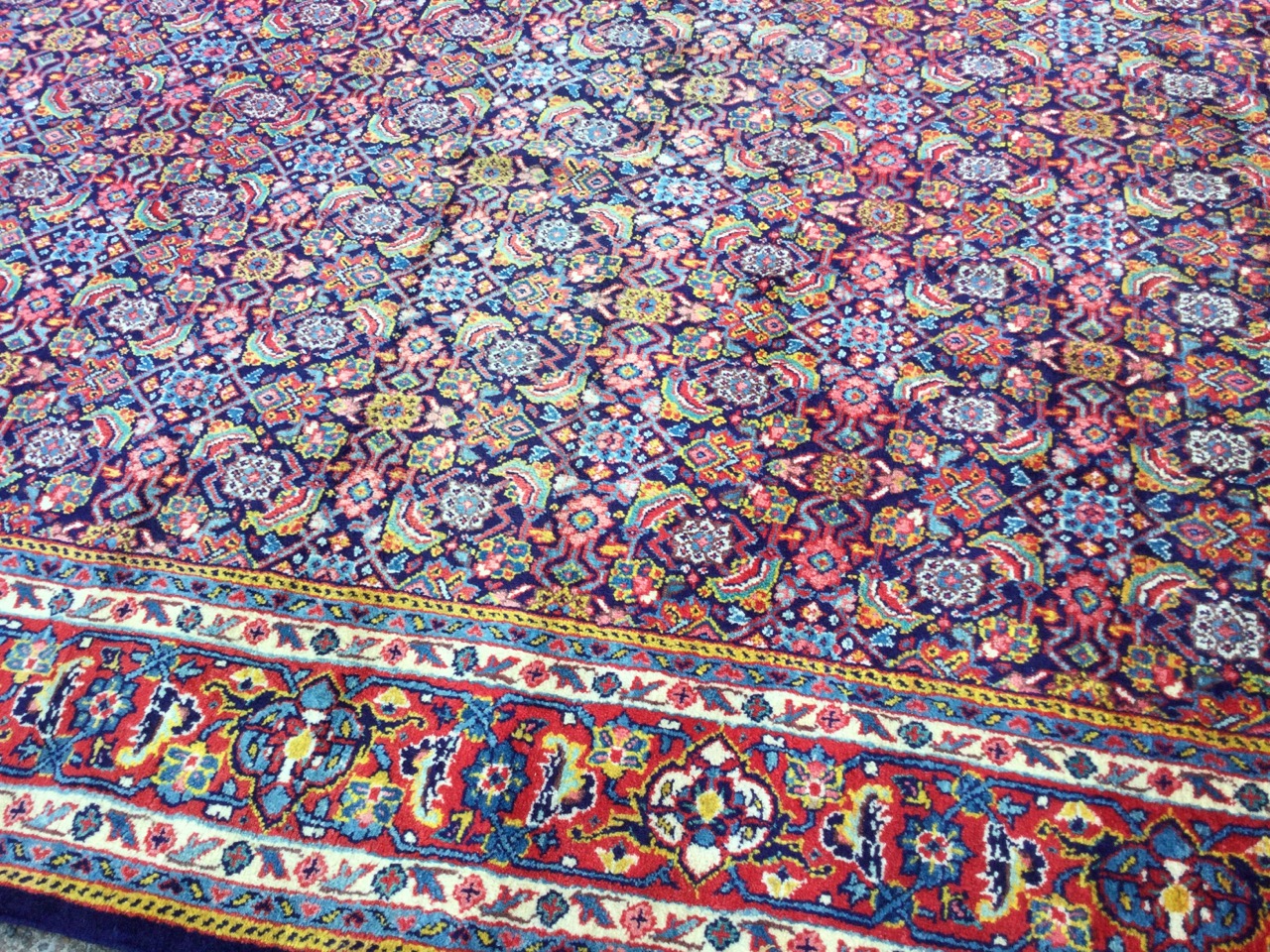 A Persian wool rug woven with multi-floral grid field on blue ground, framed by frieze of linked - Image 2 of 3