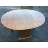 An oval oak coffee table with drop leaves on rectangular supports with batten feet, the gates with