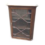 A stained Edwardian mahogany corner cabinet with moulded dentil cornice above an astragal glazed