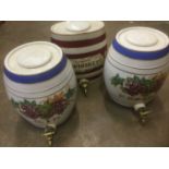 Three large ceramic spirit barrels, each with painted ornament, approximately 34cm high