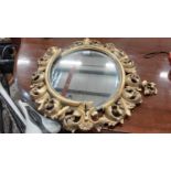 Oval bevelled wall mirror in ornate gilt frame, 66cm high, 52cm wide