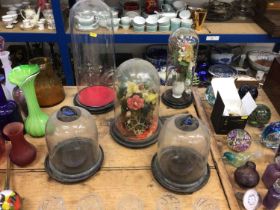 Three antique glass domes (two with artificial flowers) together with two glass-domed lanterns with