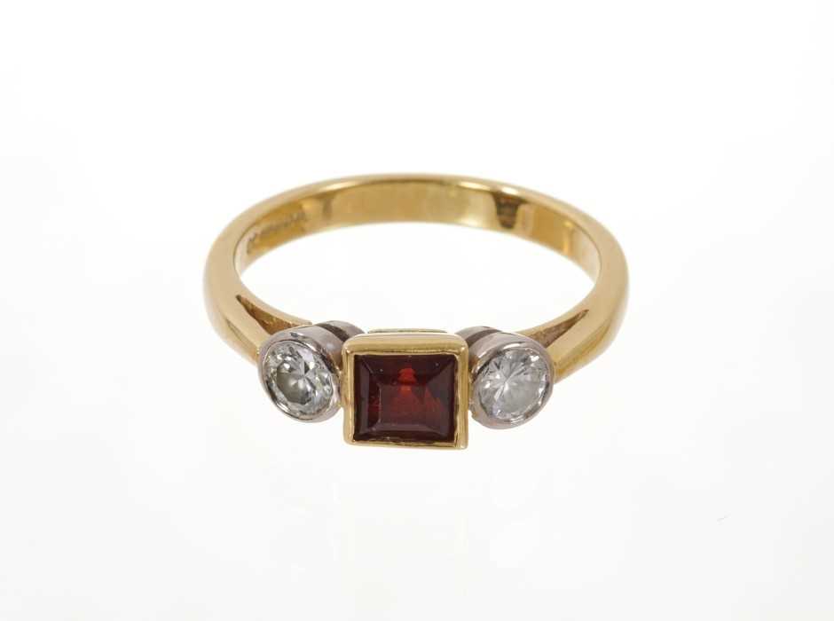 Garnet and diamond three stone ring with a square step cut garnet flanked by two round brilliant cut