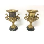 Pair of gilt metal urns, on marble pedestals