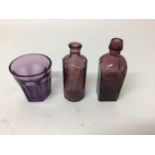 Amethyst tinted glass medicine bottle, another, and a small amethyst glass beaker