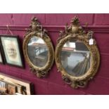 Pair of Victorian gilt gesso oval mirrors, with oval vacant cartouche crests and scroll and foliate