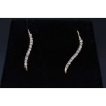 Pair of gold (585) earrings, each with a serpentine line of eleven synthetic white stones