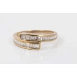 Diamond crossover ring with channel set baguette cut diamonds in 9ct yellow gold setting