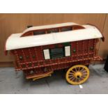 Doll's red painted caravan with yellow cart wheels, white roof and green decoration