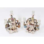 Pair of Sitzendorf porcelain three-branch figural candelabra, polychrome painted on scrollwork feet,