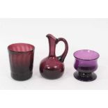 A 19th century amethyst tinted glass wrythen beaker, a small jug and a small baluster shaped bowl