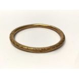 Yellow metal bangle with engraved scroll decoration
