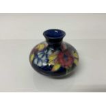 Moorcroft pottery squat vase with floral decoration on blue ground, impressed marks to base, 8.5cm h
