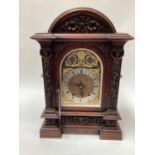 A late Victorian carved oak case chiming mantel clock, the arched brass dial with slow/fast and chim