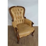 Victorian-style buttoned leather upholstered armchair on carved scroll supports