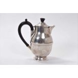 1930s silver hot water jug of compressed baluster form, with hinged domed cover and ebony loop handl