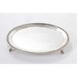 Late Victorian silver card tray of oval form, with bead border, on four ball and claw feet