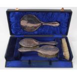 George V silver backed dressing table set comprising hand mirror and three brushes with engraved flo
