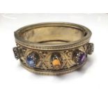Antique silver gilt cuff bangle set with five various coloured gem stones and applied leaf decoratio