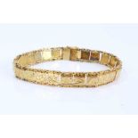 Yellow metal panel bracelet with engraved scroll decoration