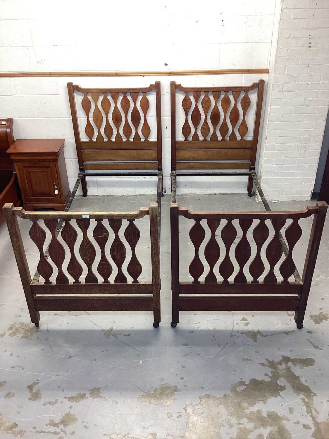 Pair of Edwardian Arts & Crafts single bedsteads, in the manner of Liberty’s