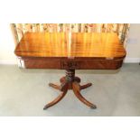 Regency mahogany card table with rounded rectangular fold-over top, on turned column and four carved