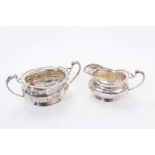 George V silver milk jug of cauldron form, with faceted decoration and scroll handle, together with