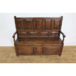 18th century Welsh oak panelled settle, with fielded panel back and solid seat flanked by scroll arm