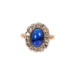 Antique diamond and synthetic sapphire ring with an oval cabochon synthetic blue sapphire surrounded