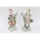 A pair of Derby figural candlesticks, late 18th century, each standing next to floral encrusted tree