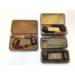 Three cases of two briar pipes, the first with one hallmarked 1899, the second unmarked with amber s