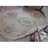 A vintage Chinese washed wool oval rug with floral motifs and decorative border on beige ground -