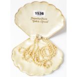 A vintage Pompadour Pearls clamshell pattern case containing a three strand simulated pearl