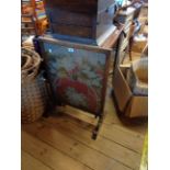 An old stained oak framed fire screen with floral tapestry panel under glass