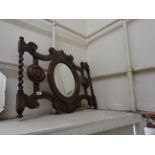 An early 20th Century oak hall mirror with bevelled oval plate, flanking coat hooks and barley twist