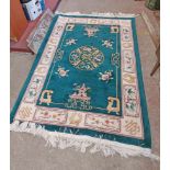 A modern handmade Chinese washed wool rug with central medallion and floral panels on green ground