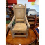 An antique style oak child's panel back elbow chair with solid seat, set on turned supports and