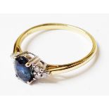 A hallmarked 750 gold ring, set with central oval sapphire and six small flanking diamonds - boxed