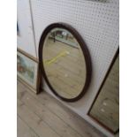 A 1920's stained oak framed bevelled oval wall mirror