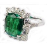 A marked 18k white metal ring, set with large central square cut emerald within a sixteen stone
