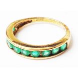 A 375 gold ring with half band of channel set emeralds - boxed
