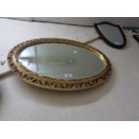 An ornate gilt framed bevelled oval wall mirror