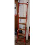 A modern step ladder/extension ladder with wooden treads and red painted finish